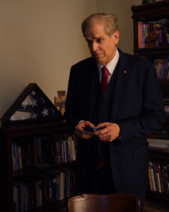 A Man Standing in a Library in a Black Suit